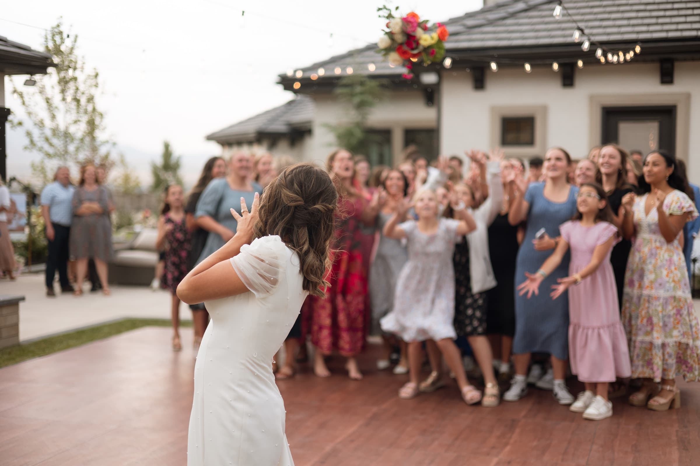 Bride tossing her bouquet toward cheering wedding guests
