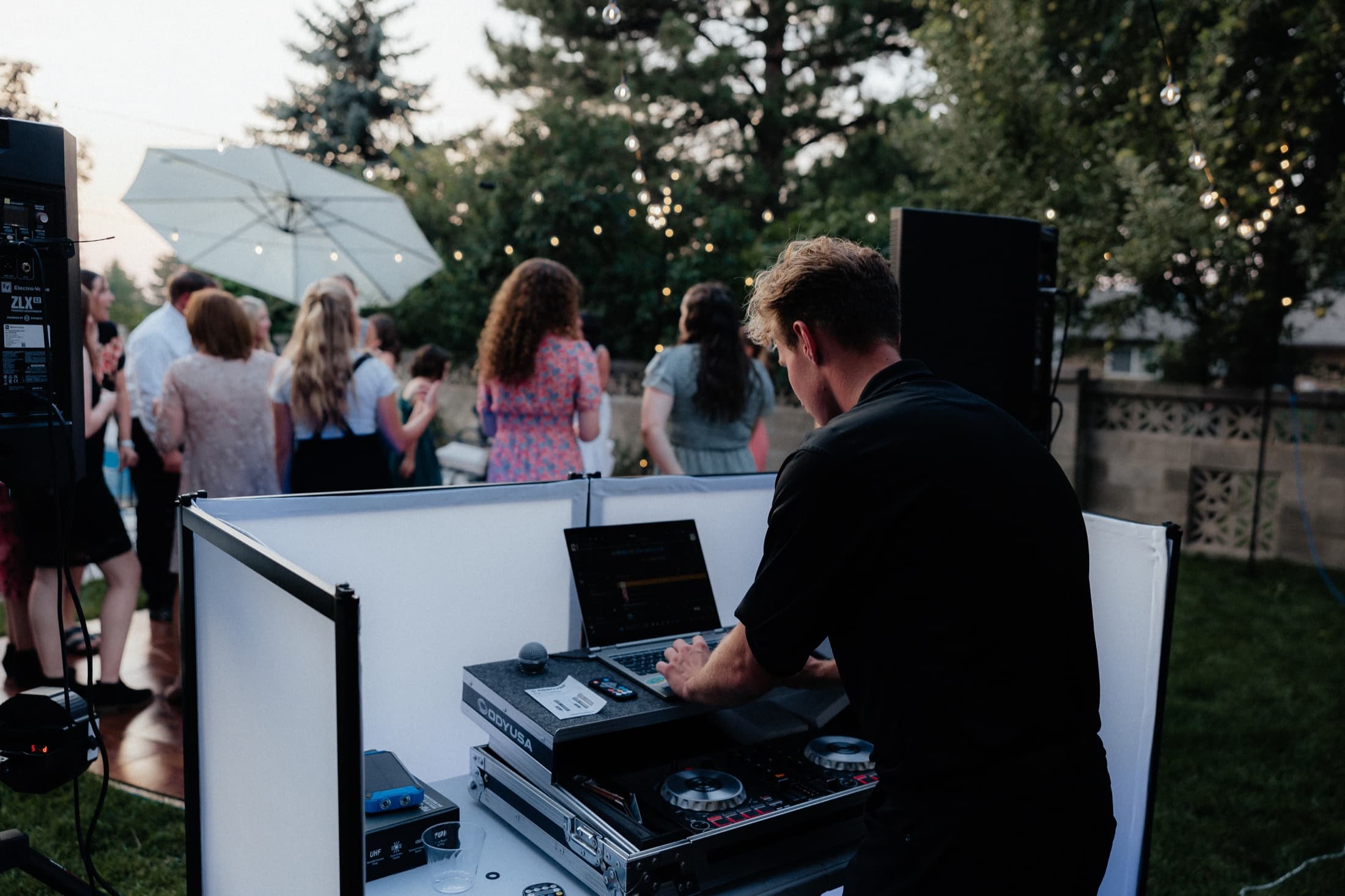 DJ Christian working behind his booth at an outdoor wedding reception