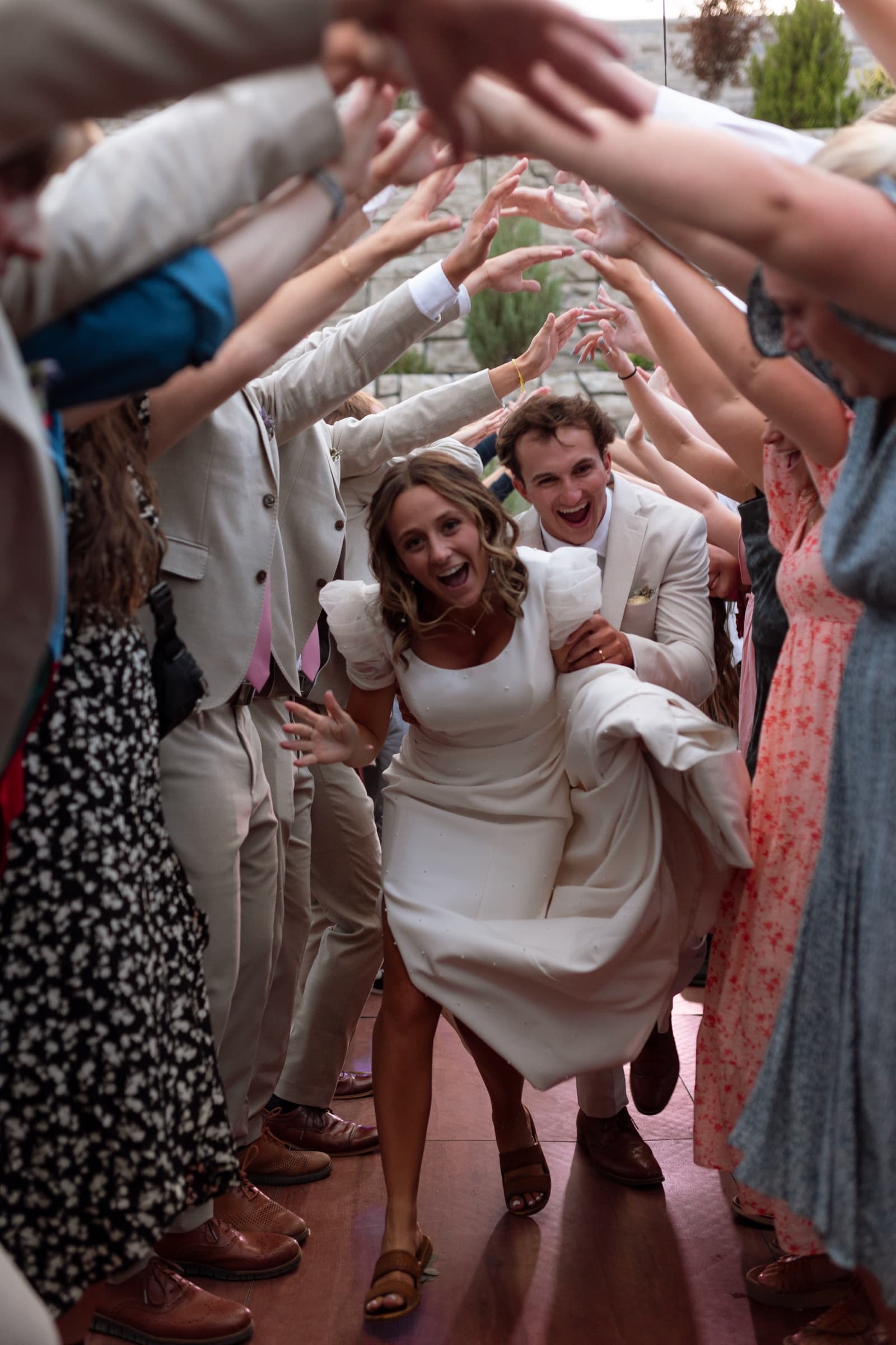 Newlyweds laughing as they run through a tunnel of guests
