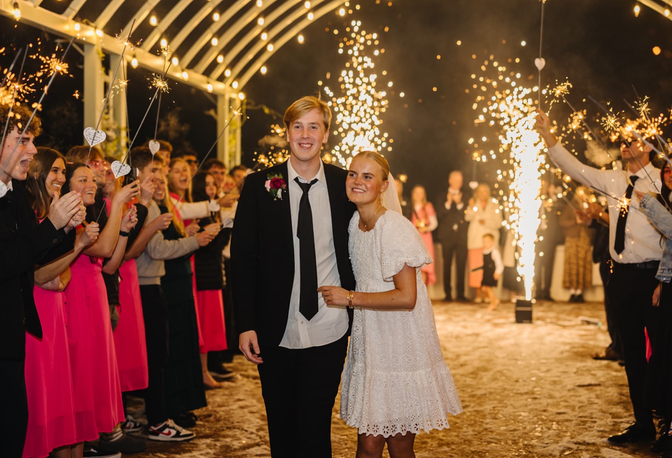 Newlyweds smiling during a coordinated sparkler send-off