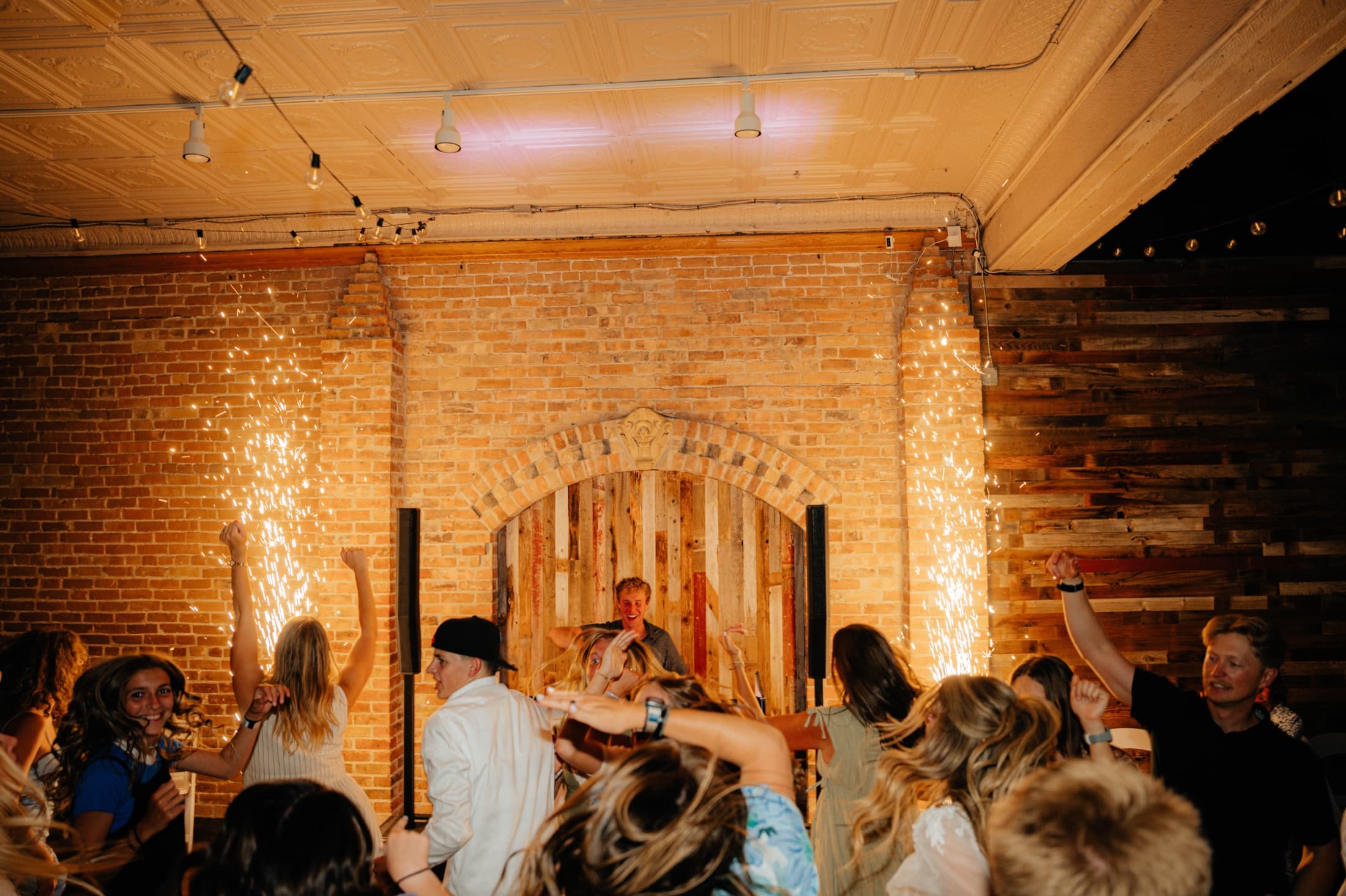 Wedding dance floor warmly lit against a brick reception wall