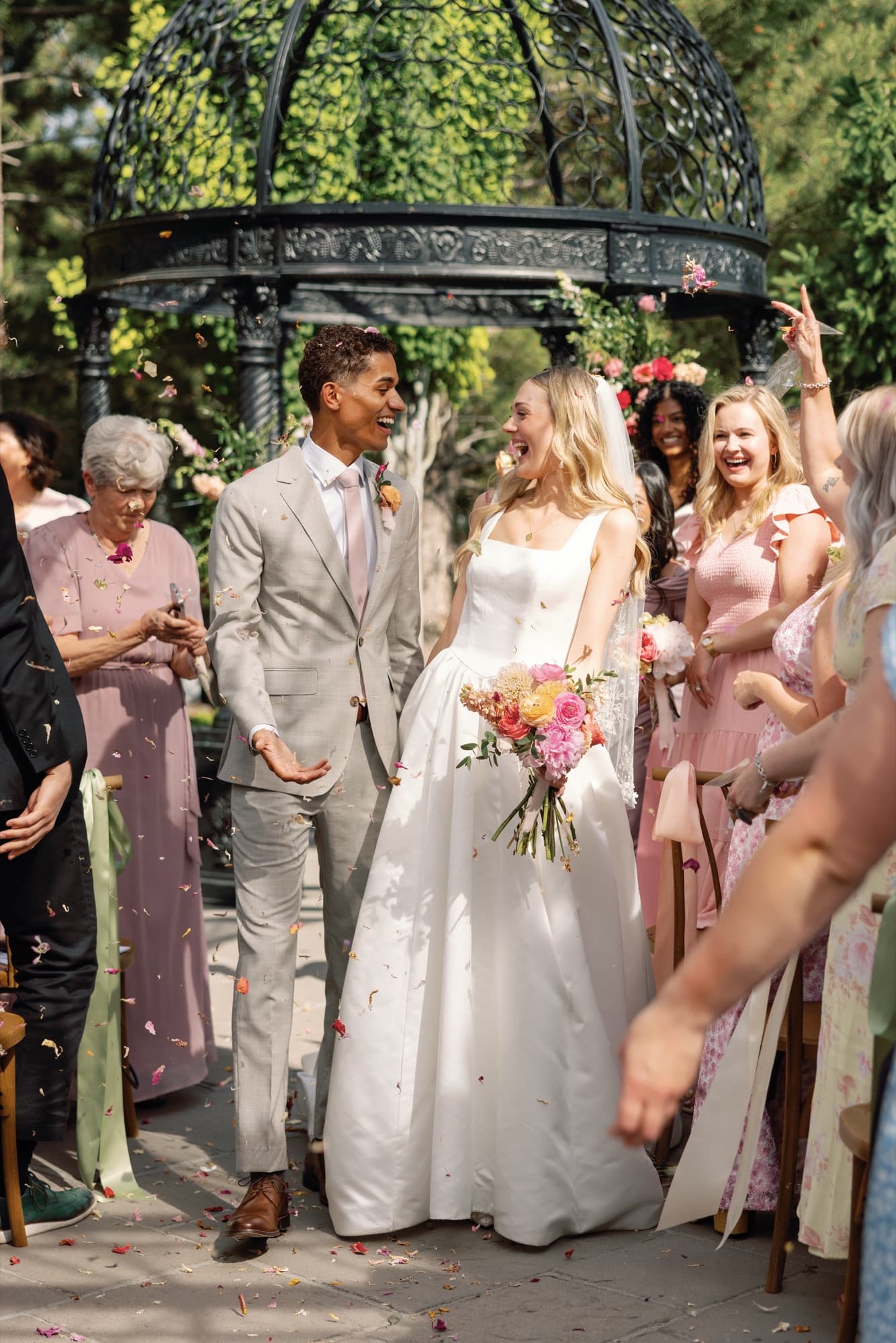 Newlyweds celebrating outdoors as guests toss flower petals