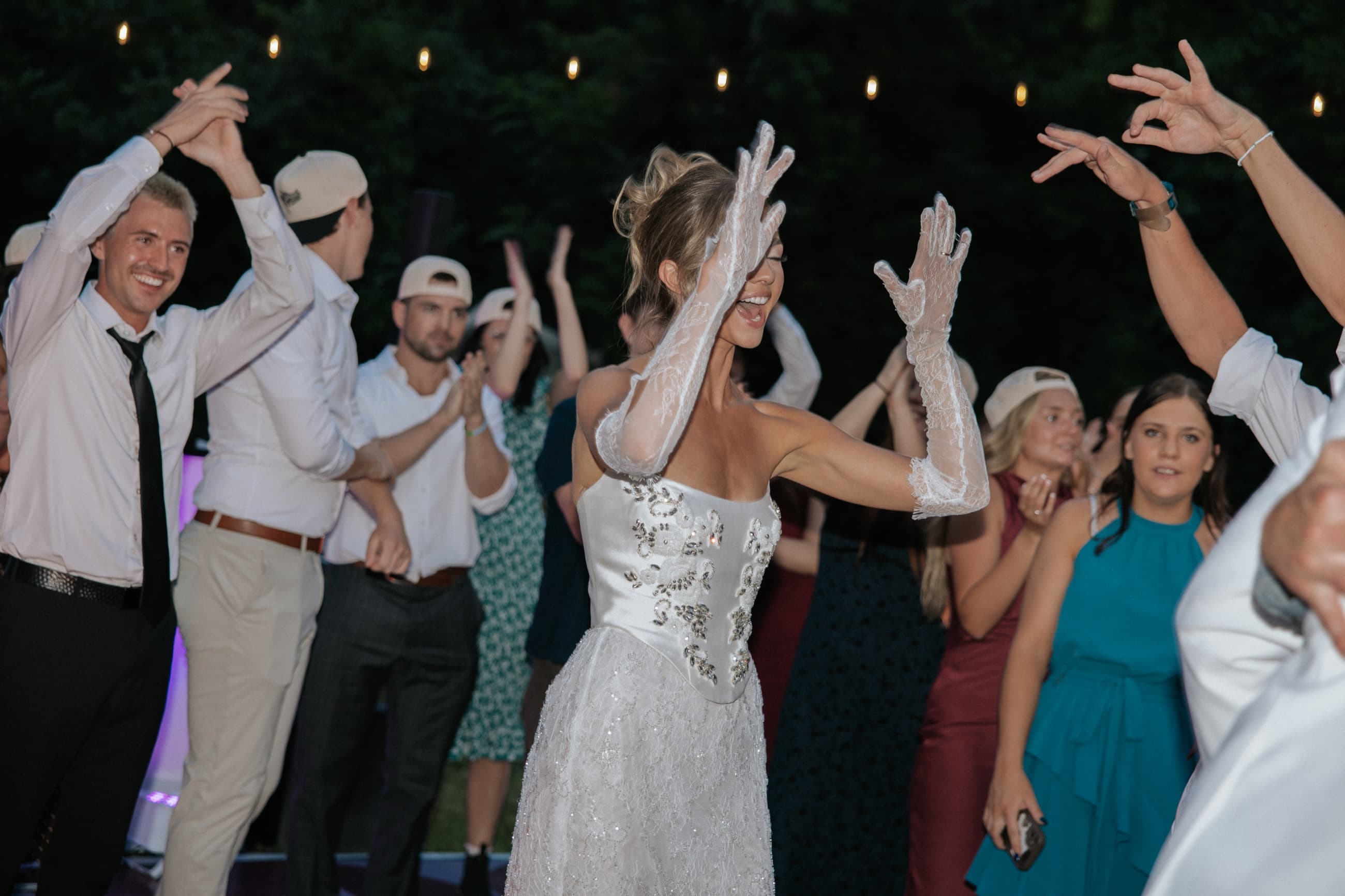 Bride dancing with guests in the middle of a packed outdoor wedding dance floor