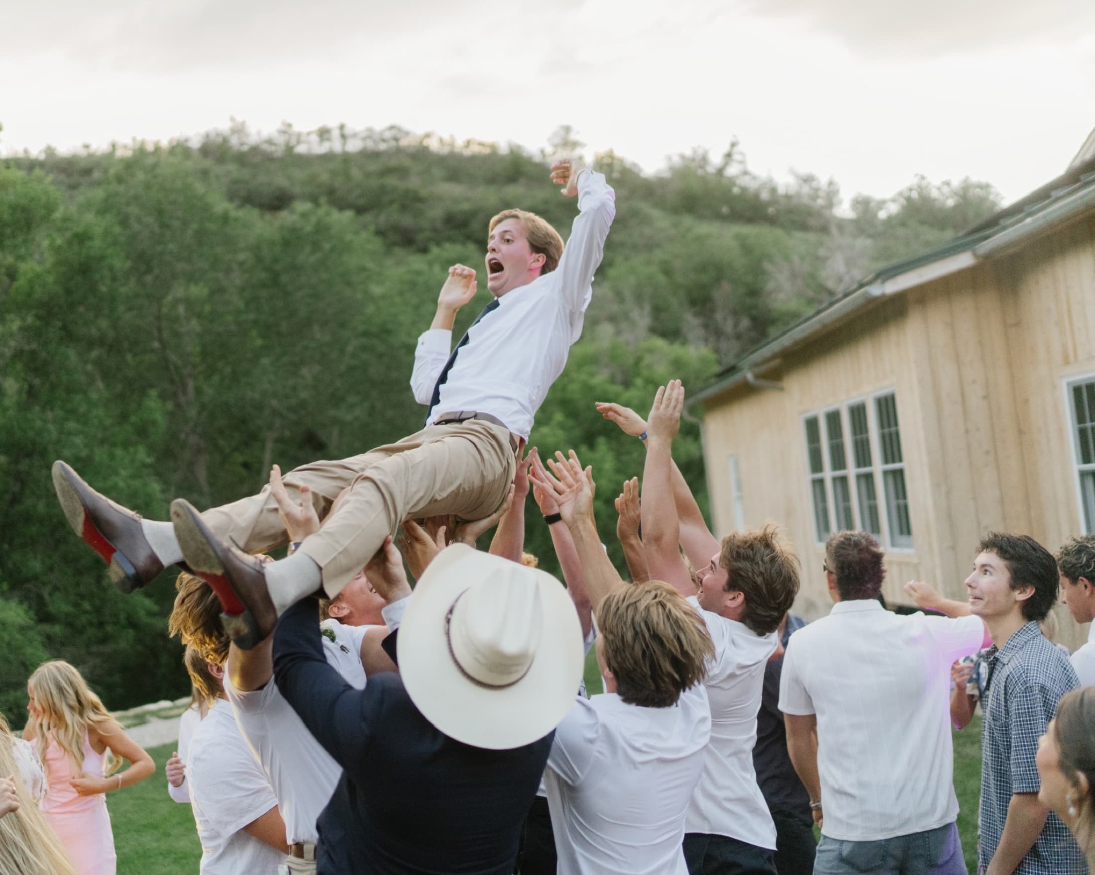 Wedding guests lifting the groom above a packed outdoor dance floor