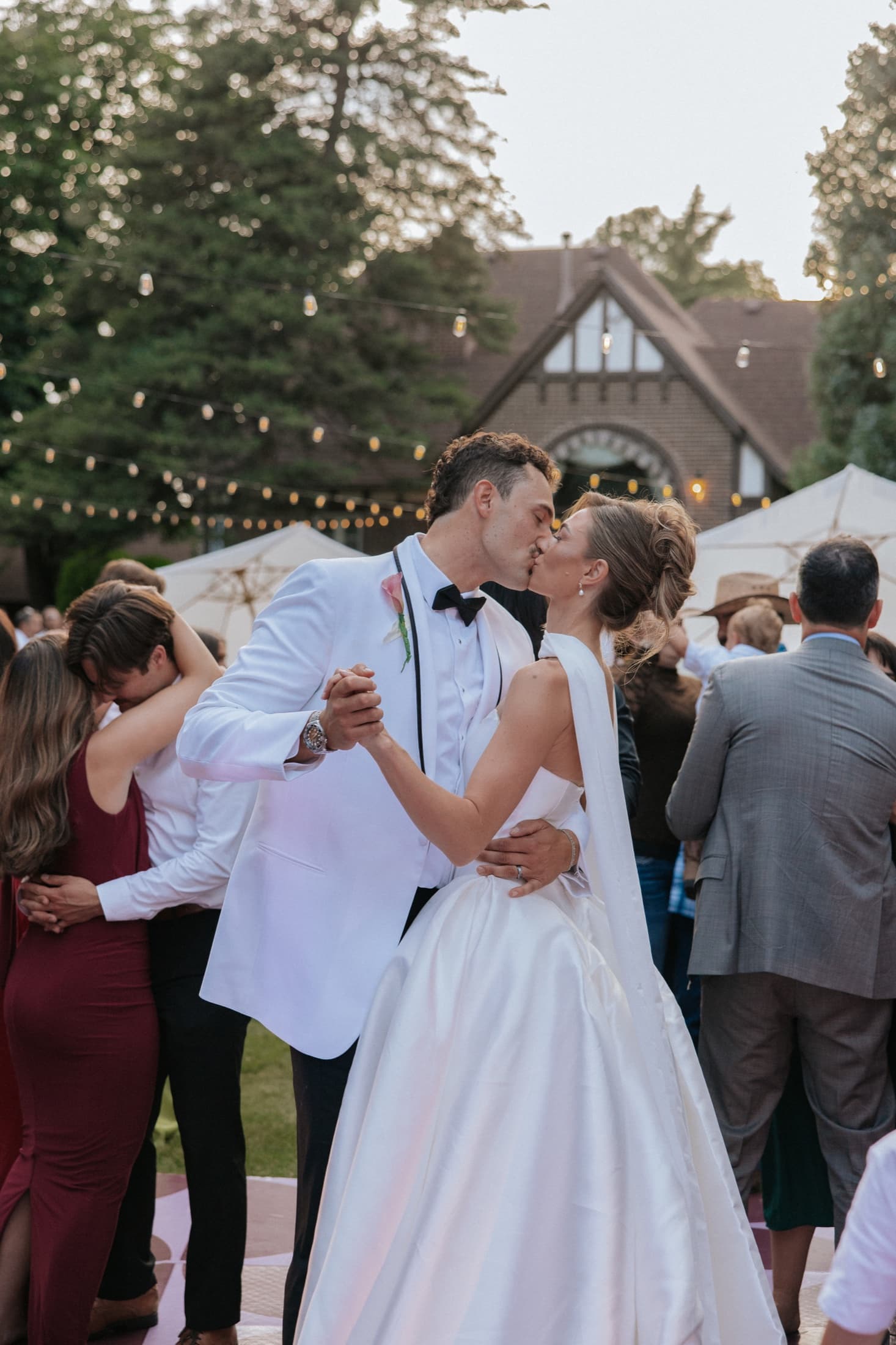 Newlyweds kissing during their first dance as guests celebrate around them