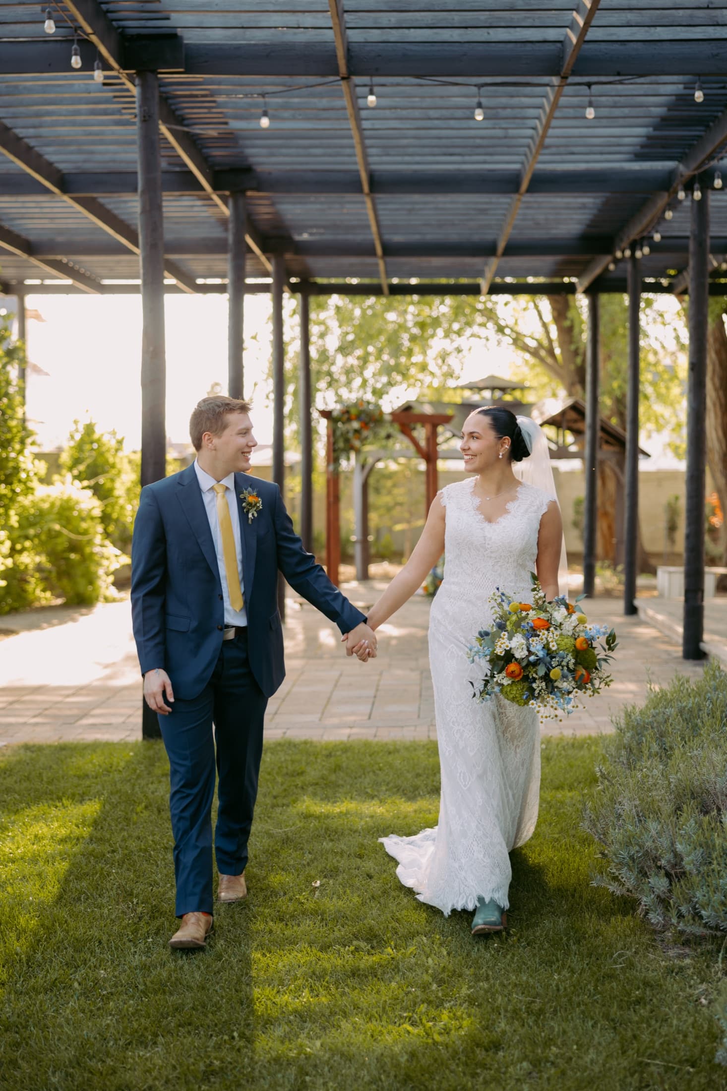 Newlyweds walking hand in hand during their outdoor wedding reception