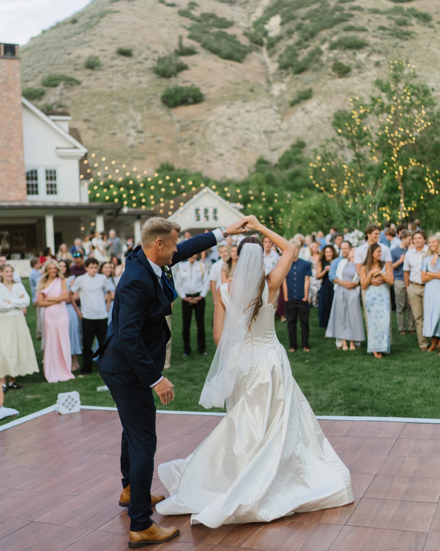 Bride sharing a parent dance as wedding guests look on