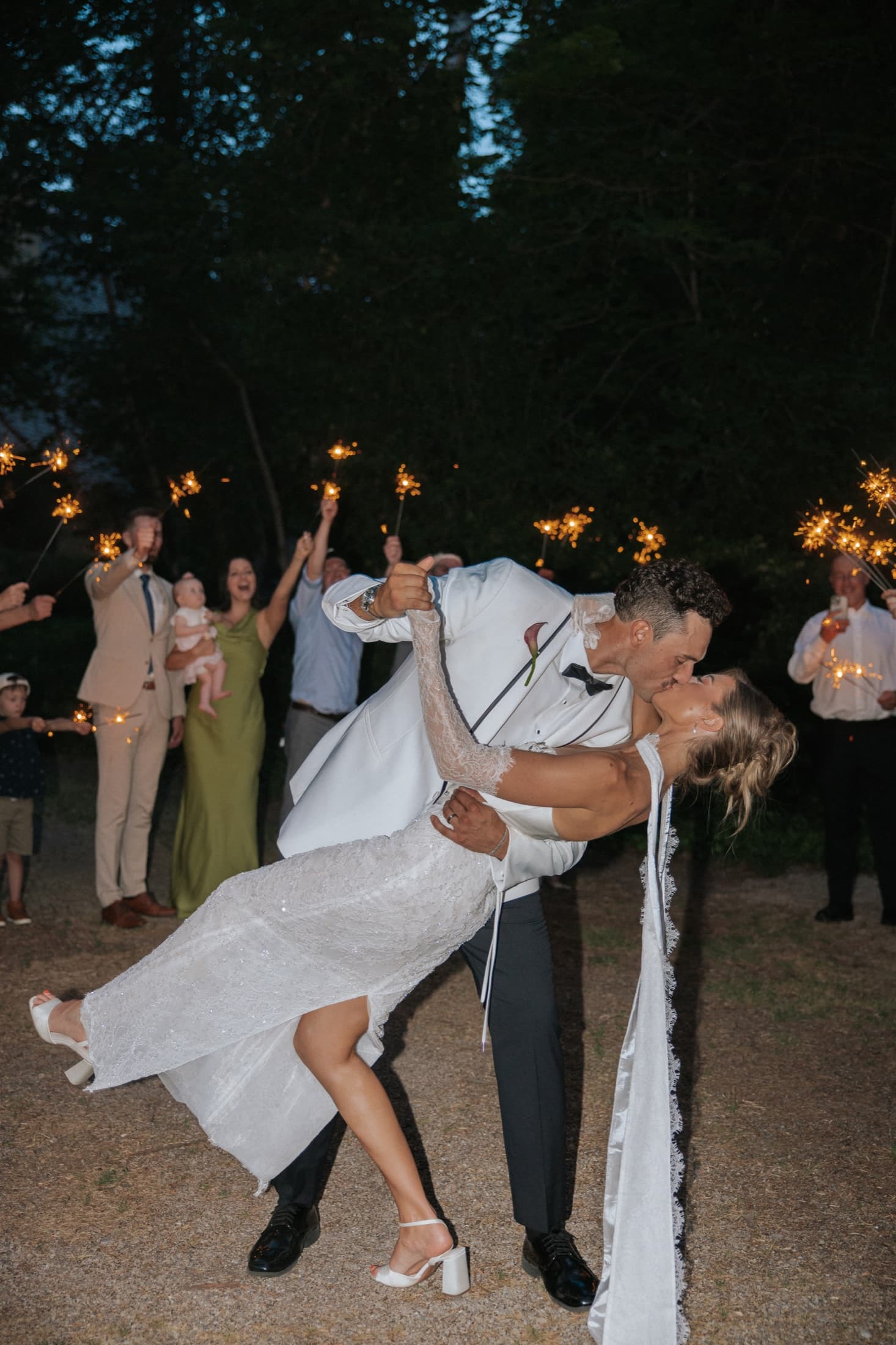 Newlyweds dipping for a kiss at the end of their sparkler send-off
