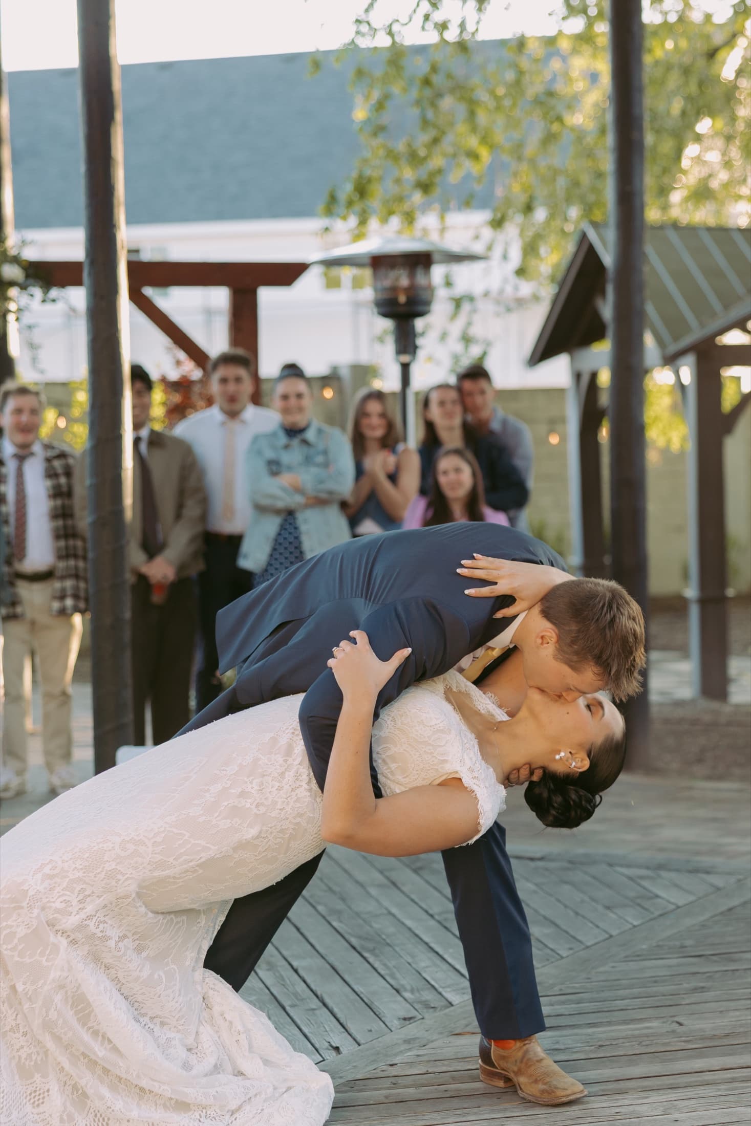 Newlyweds sharing a dramatic dip and kiss during their outdoor reception